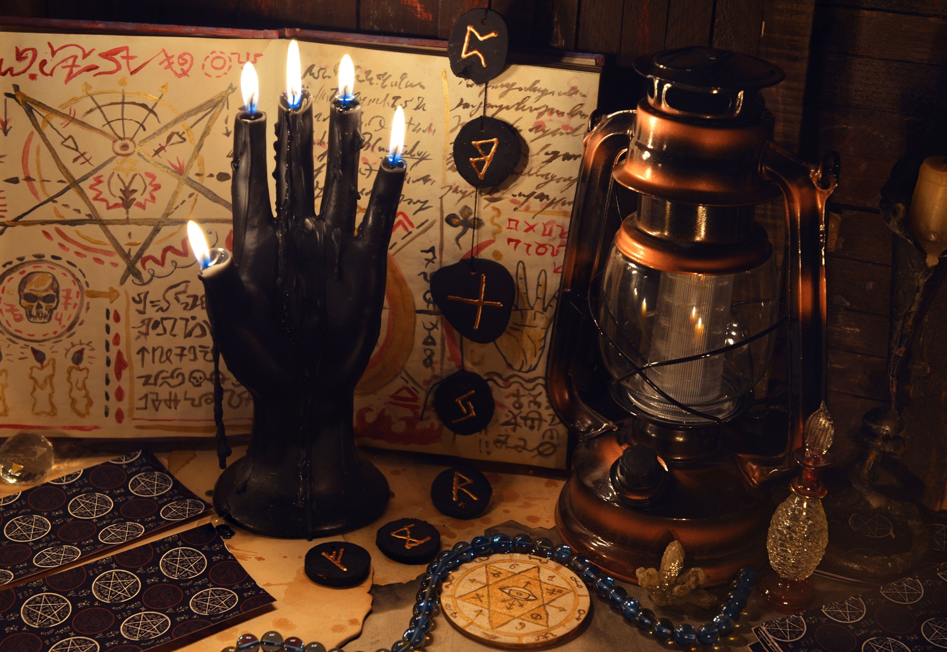 Mystic still life with tarot cards, runes and black candle as scary hand on witch table. Occult, esoteric, wicca, Halloween and gothic concept. No foreign language, all symbols are fictional.