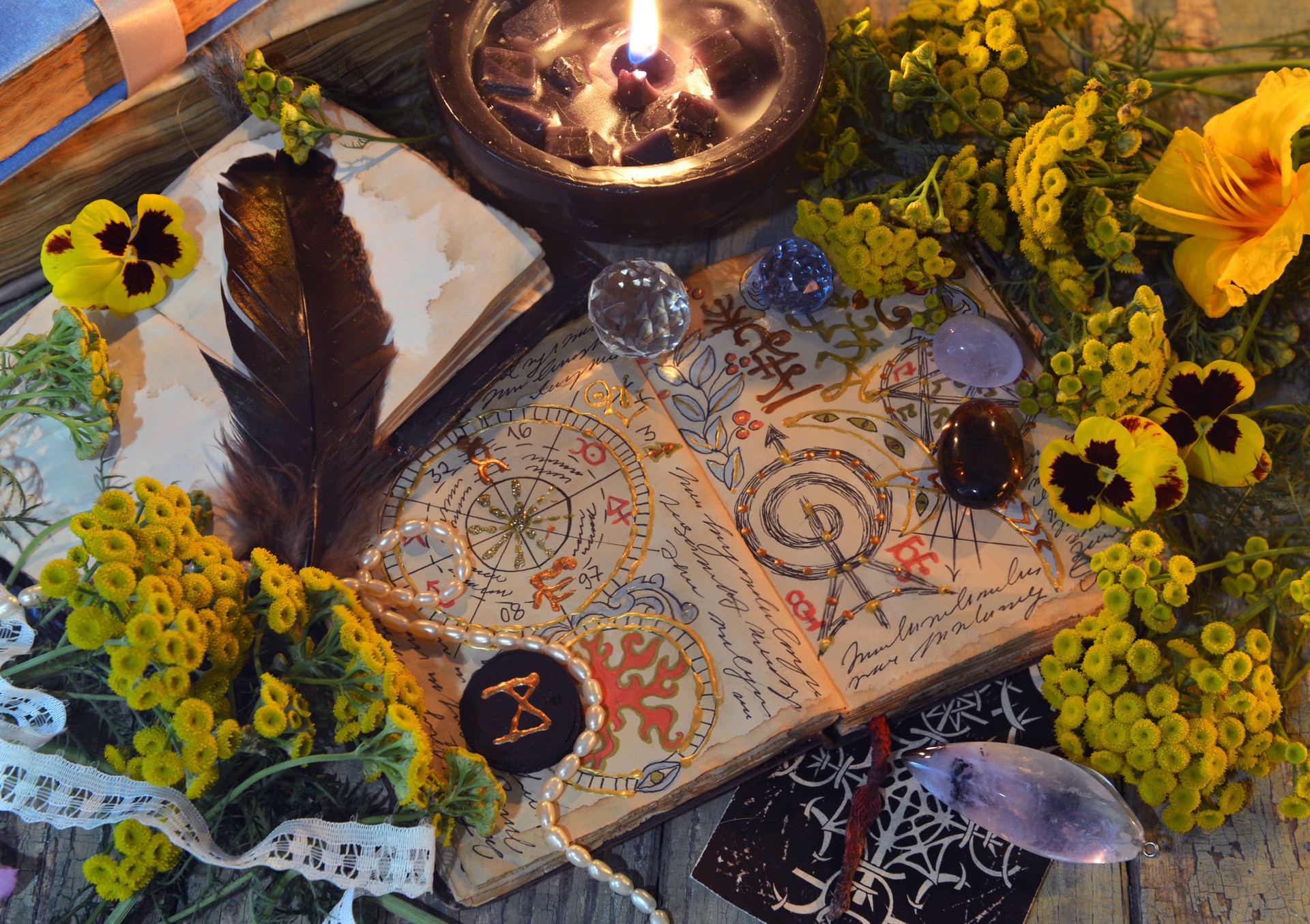 Mystic still life with decorated magic book of spells, tarot card, tansy flowers, crystals, black candles and witchy ritual objects on old table. Occult, esoteric and wicca concept