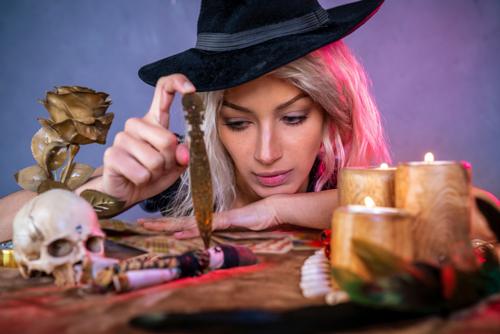 Vodoo girl with knife on table and witch hat