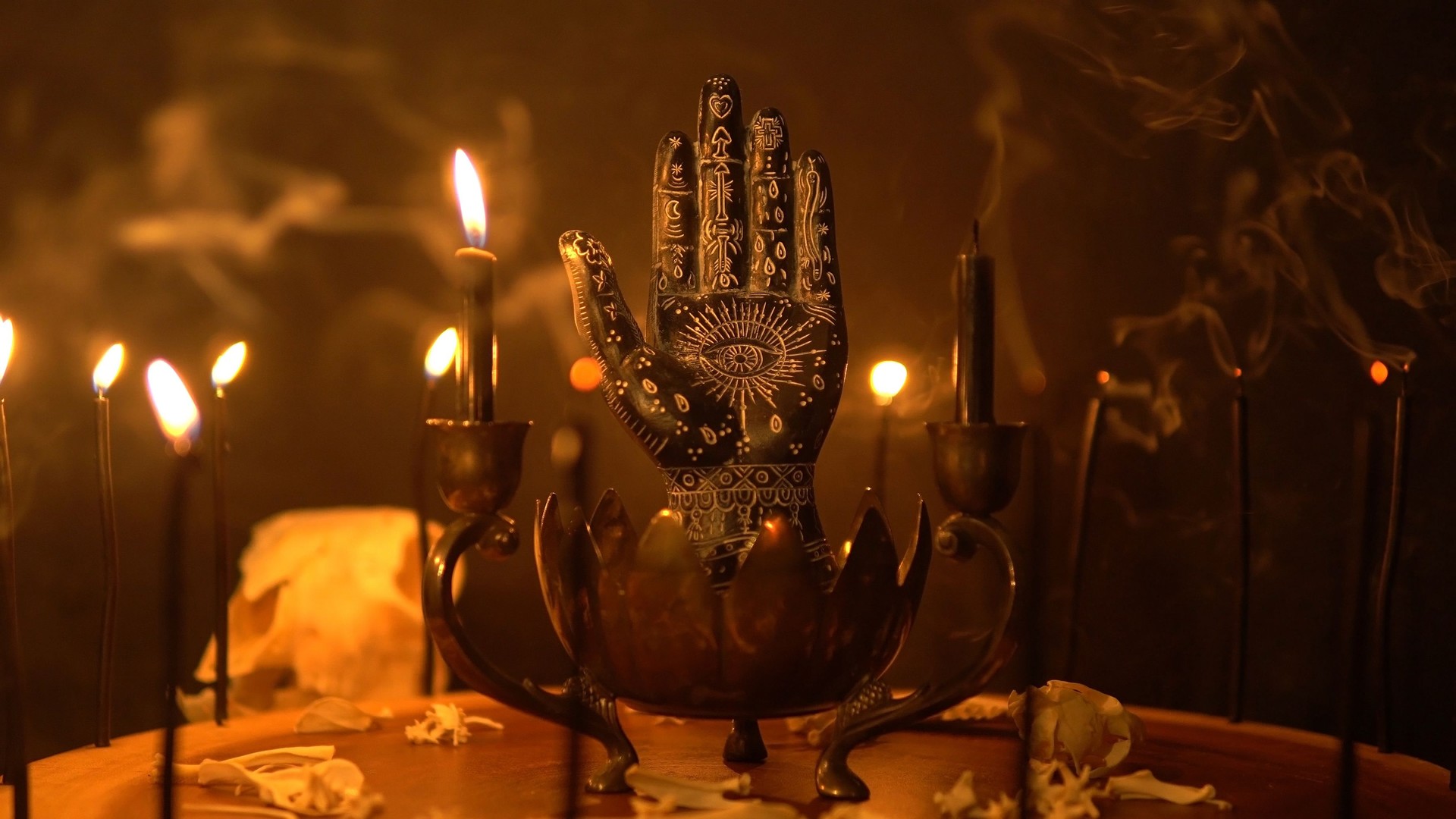 Palmistry and table statue of the black hand at fortune teller table. Mystic palm reading and magical black candles on candle holder. Occult knowledge and occultism. Spiritual mood.