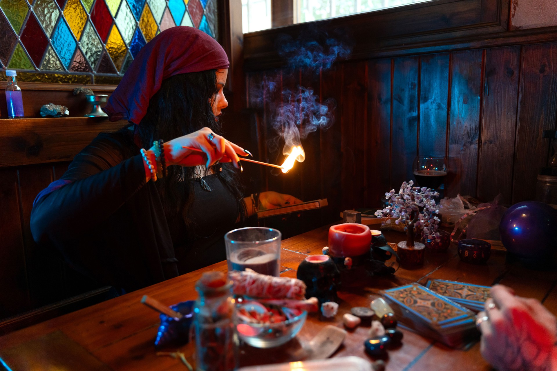 Fortune teller reading tarot cards and burning incense in mystical room