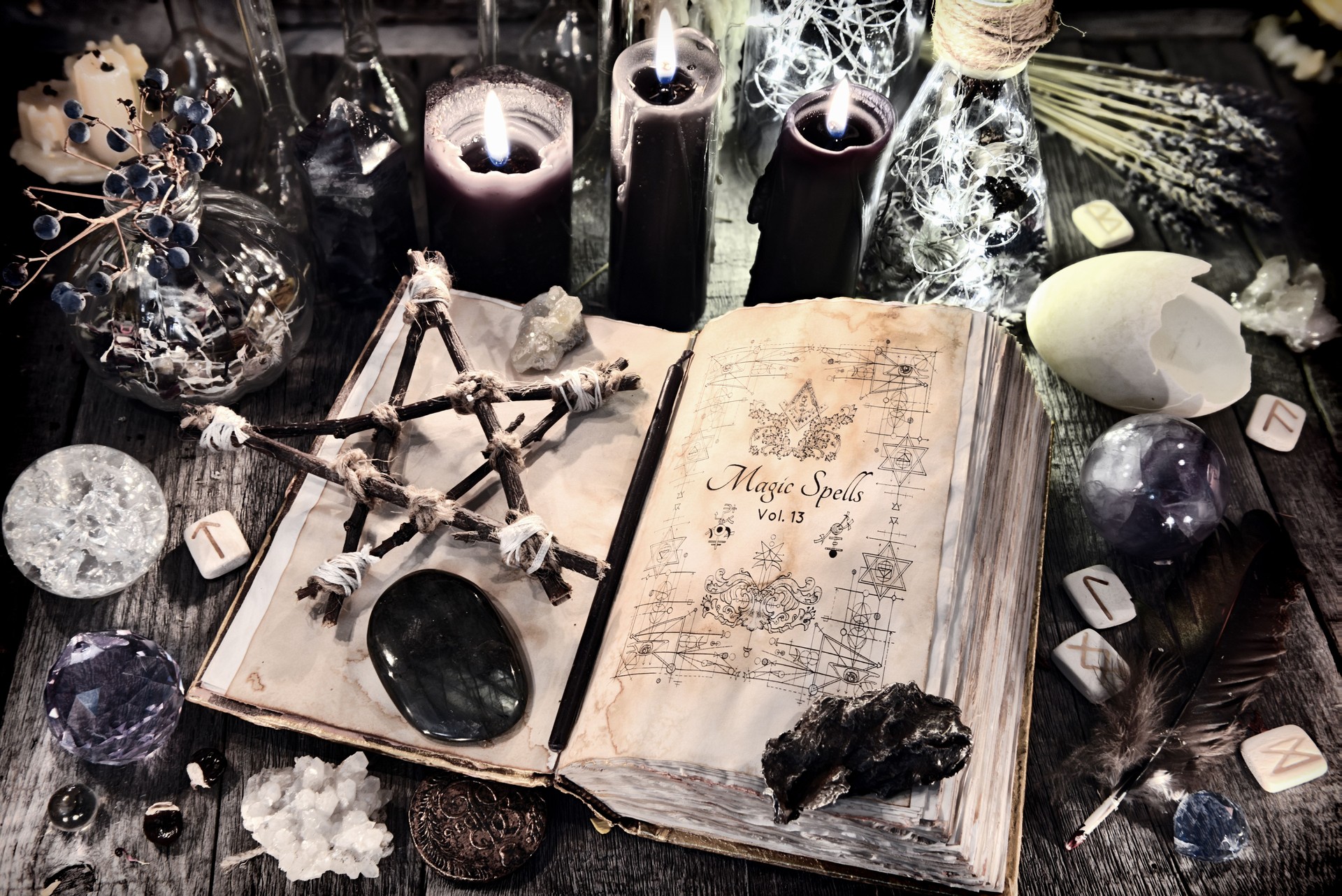 Open witch book with pentagram, black candles, stones, crystals and magic ritual objects